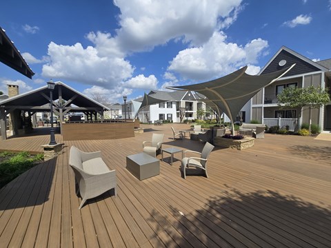 A wooden deck with chairs and tables is surrounded by buildings at Reserve of Bossier City Apartment Homes Bossier City, LA 71111