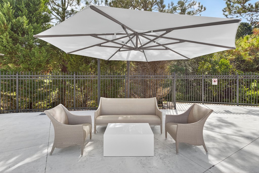 A white umbrella shades a set of outdoor chairs and a table.
