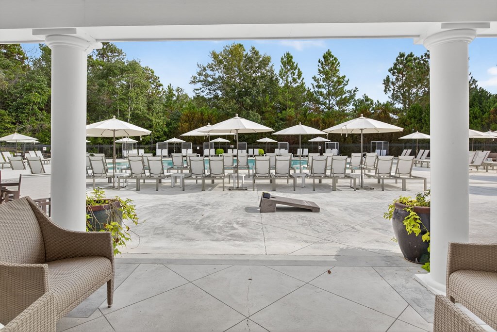 A patio with chairs and umbrellas overlooking a pool.