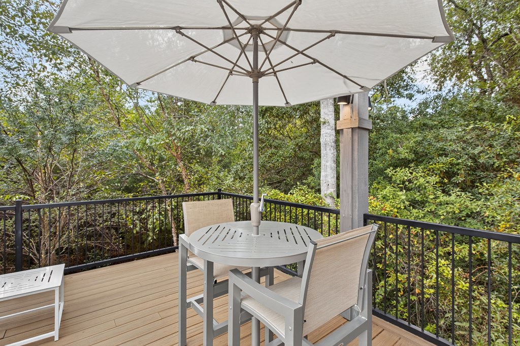A patio table with a white umbrella on a balcony.