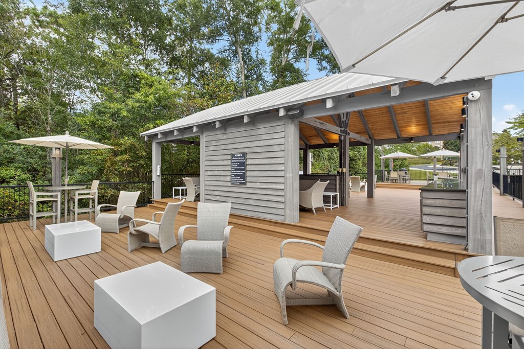 A wooden deck with white chairs and tables.