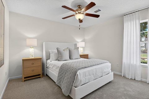 A bedroom with a bed, nightstand, and a ceiling fan.