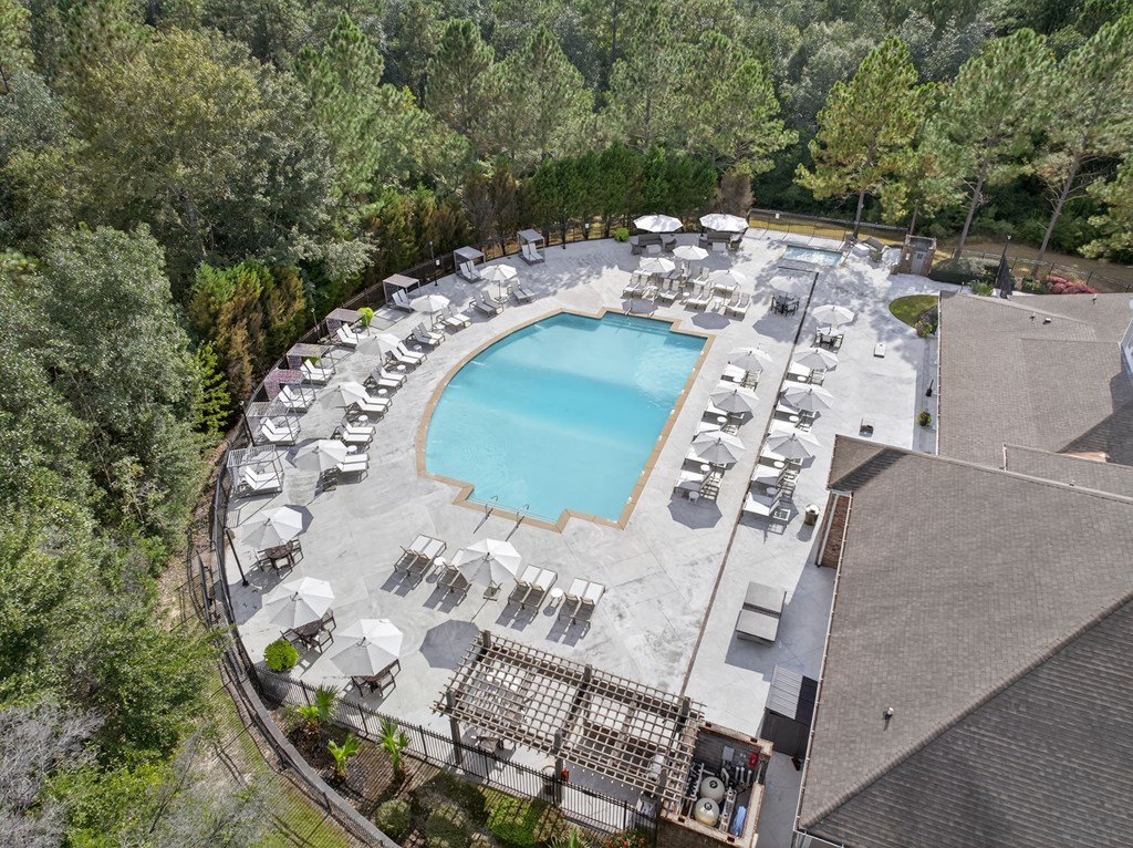 A large outdoor swimming pool surrounded by sun loungers and umbrellas.
