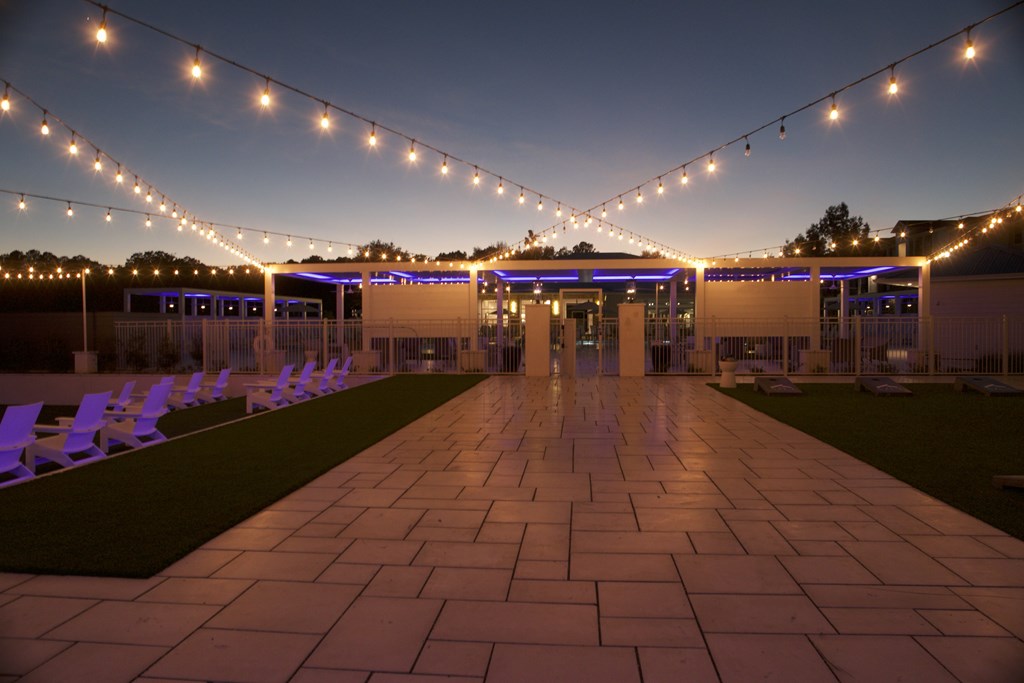 A long walkway with purple chairs and string lights on either side. at The Azul Apartment Homes, Oxford, 38655