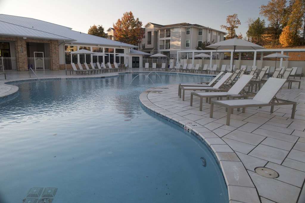 A large outdoor swimming pool with sun loungers and a building in the background. at The Azul Apartment Homes, Oxford, Mississippi