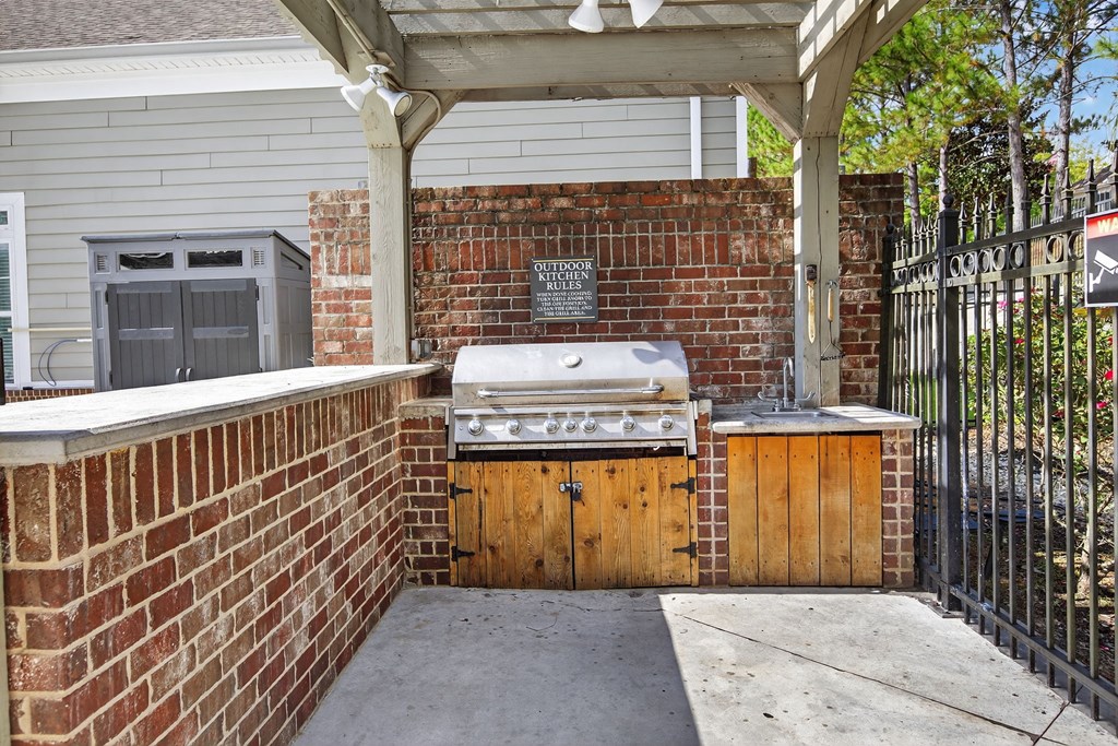 A brick wall with a grill on top and a wooden door.