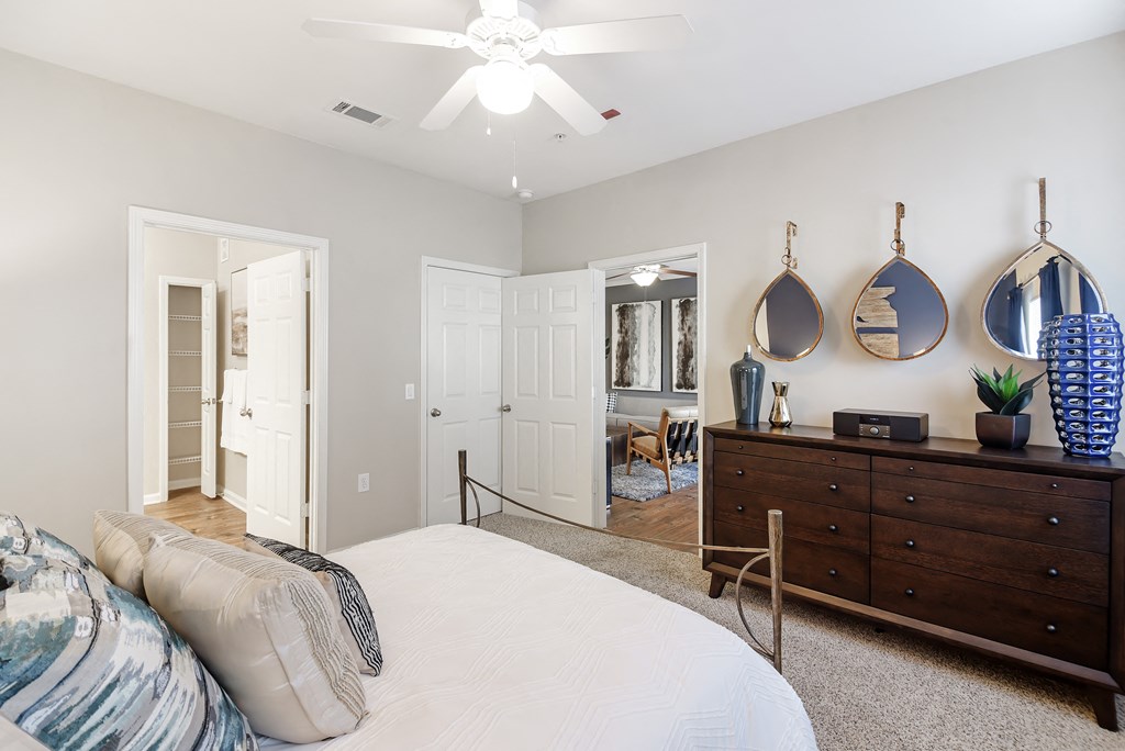 a bedroom with a bed and a dresser and a ceiling fan at Cumberland Place Apartment Homes, Texas 75703