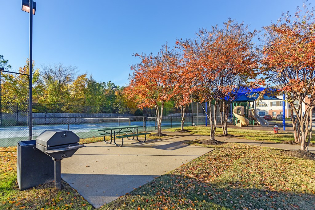 a park with a picnic table and a tennis court at Cumberland Place Apartment Homes, Tyler, TX