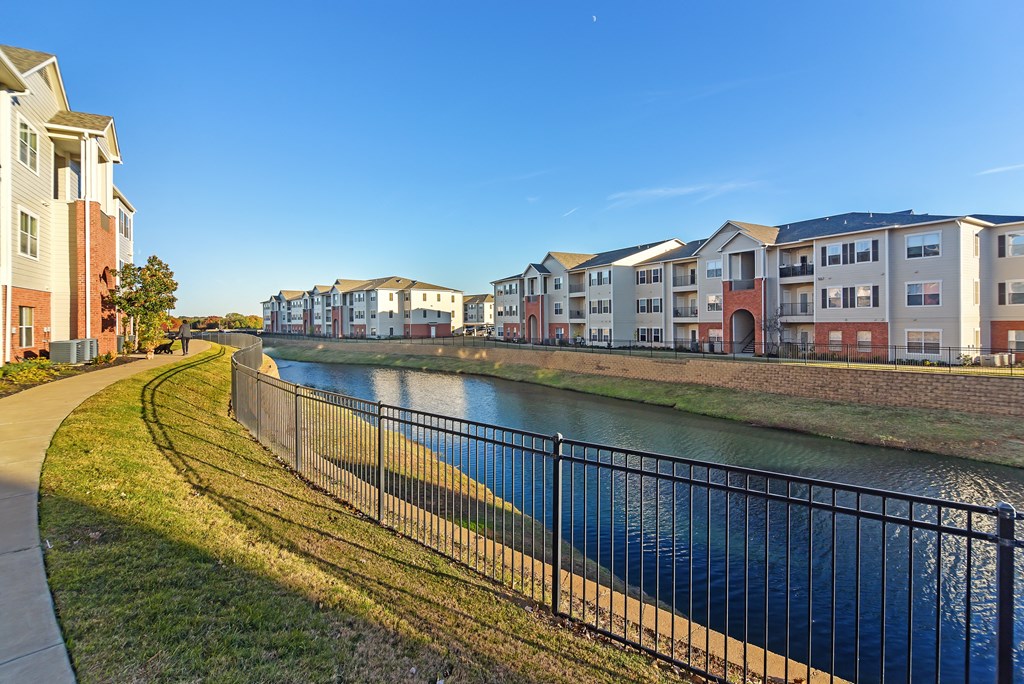 a river with a row of houses on the other side of it at Cumberland Place Apartment Homes, Texas