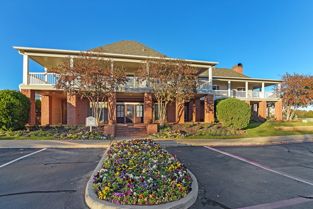 a house with a driveway and a flower garden in front of it at Cumberland Place Apartment Homes, Tyler, Texas
