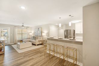 a living room with a kitchen and a couch and chairs