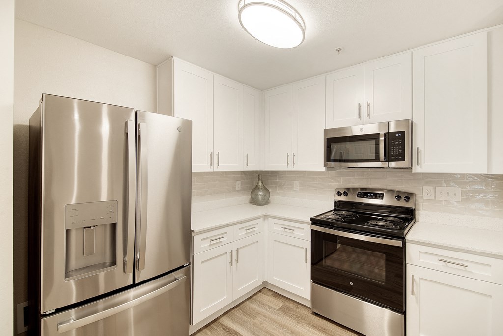 a kitchen with stainless steel appliances and white cabinets at The Azul Apartment Homes in Oxford, Mississippi 38655