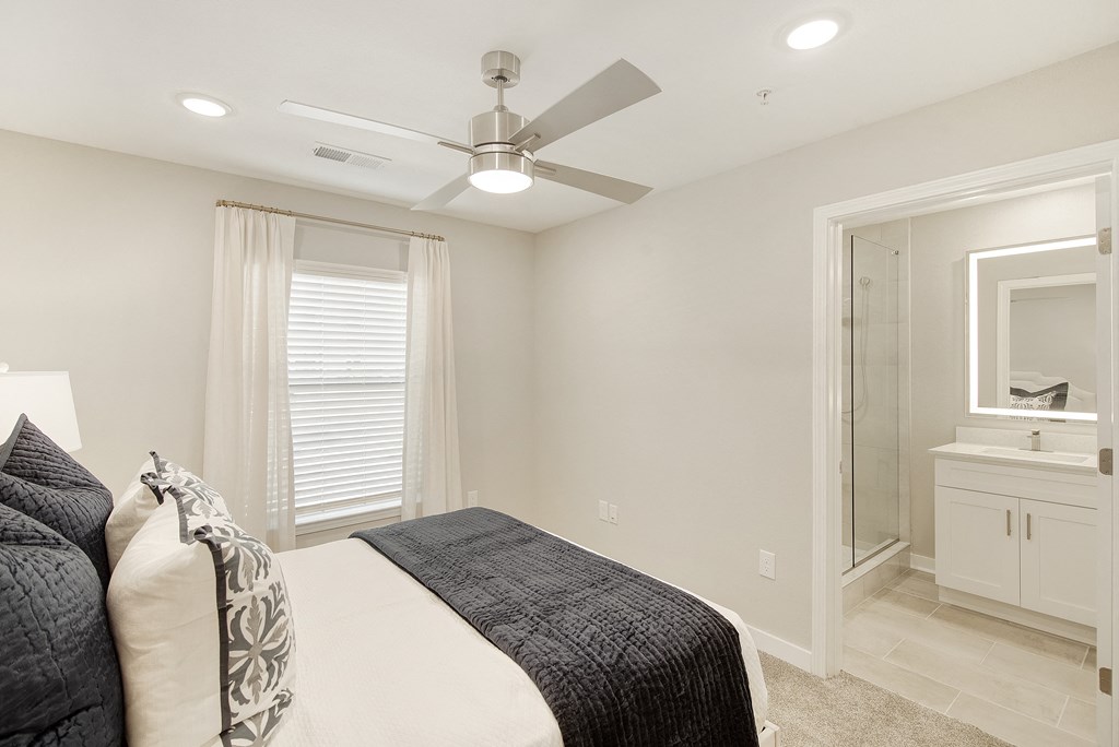 a white bedroom with a large bed and a ceiling fan at The Azul Apartment Homes in Oxford, Mississippi