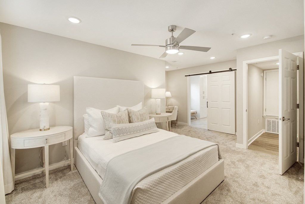 a white bedroom with a large bed and a ceiling fan at The Azul Apartment Homes in Oxford, MS