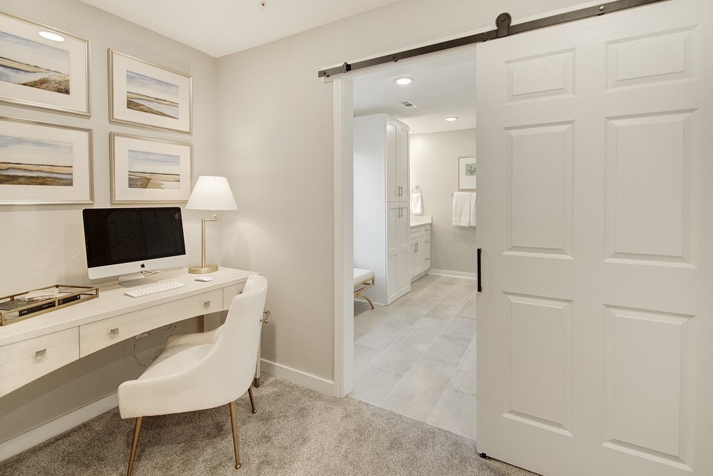 a home office with a computer desk and a door to a bathroom at The Azul Apartment Homes in MS 38655