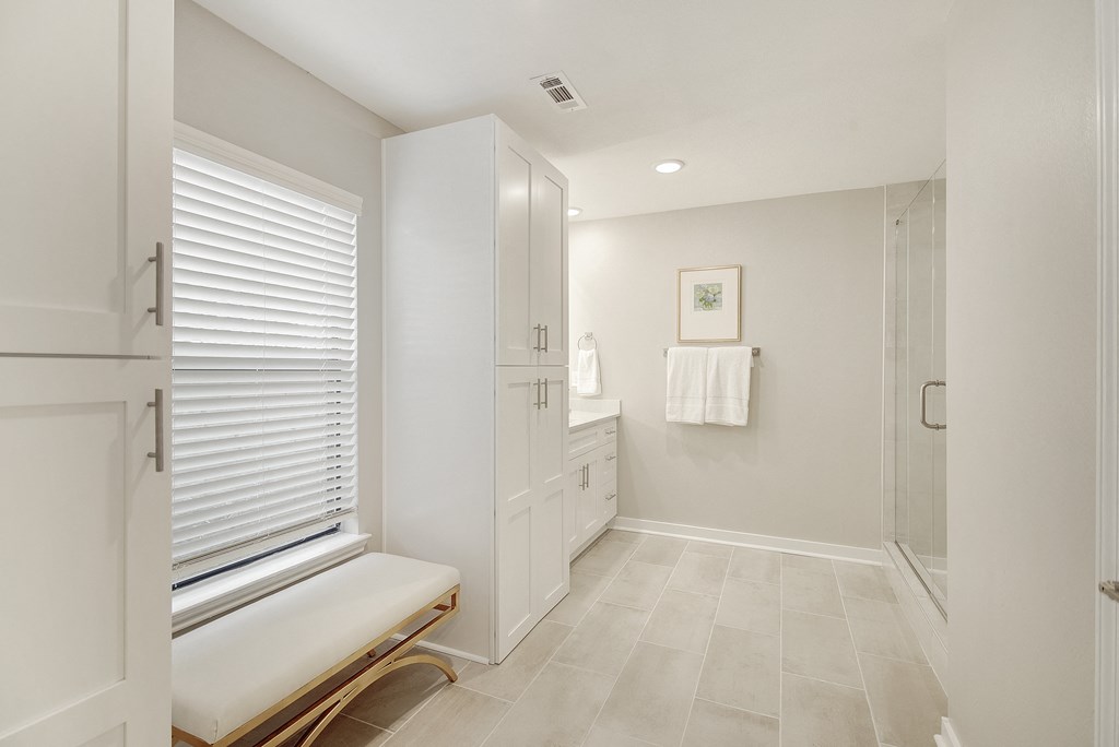 a large white bathroom with a shower and a bench at The Azul in Oxford, MS