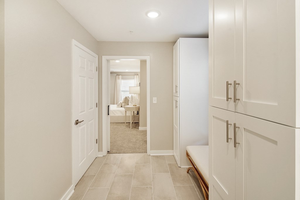 a white kitchen with white cabinets and white doors and a hallway to a living room at The Azul Apartment Homes, Oxford, Mississippi