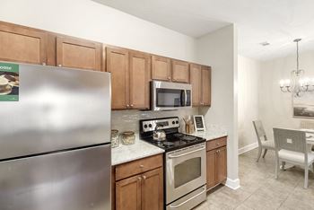 Kitchen with a stainless steel refrigerator, microwave, oven, and a dining table with chairs at Highlands Apartment Homes, Tennessee