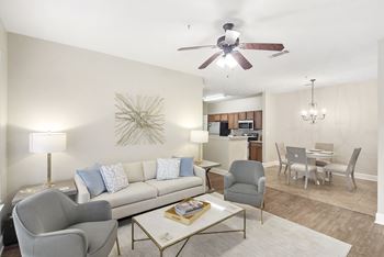 Living room with a white couch, a coffee table, and a ceiling fan with hardwood floors at Highlands Apartment Homes, Bartlett, Tennessee