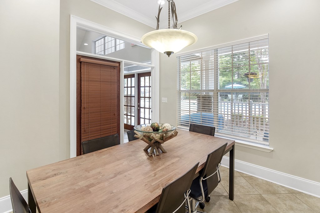 Dining room with a wooden table and chairs and a large window at Highlands Apartment Homes, Tennessee