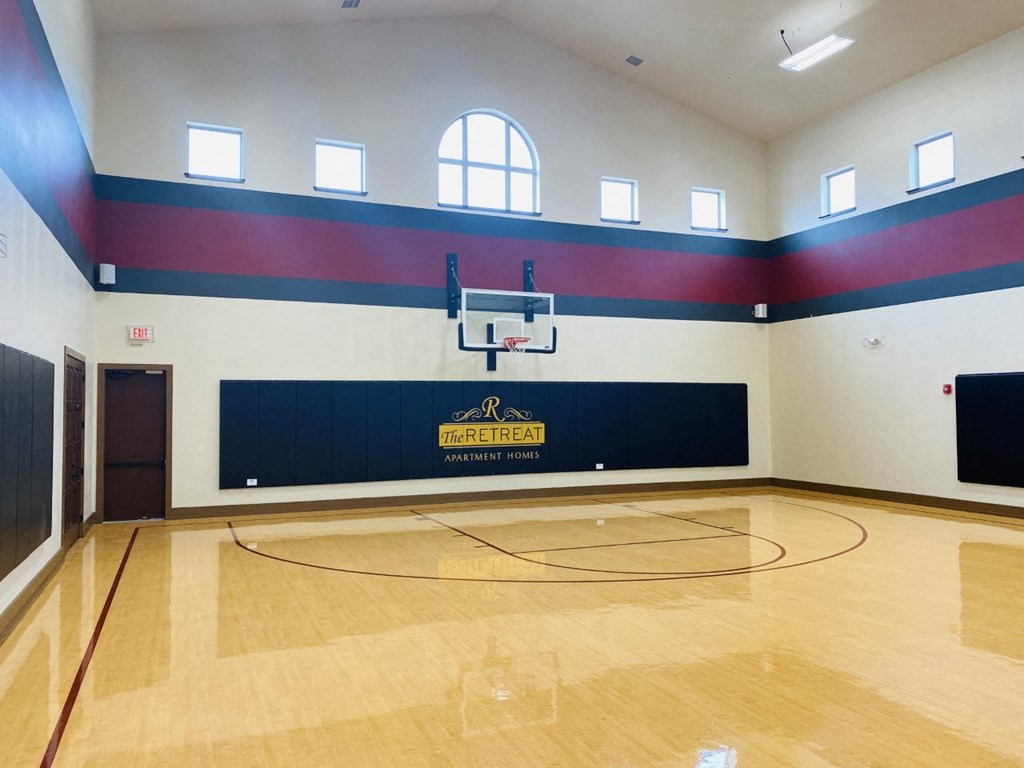 a basketball court in an empty gym with a basketball hoop at The Retreat Apartment Homes in Williston, ND 
