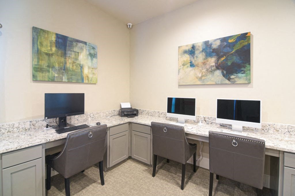 a room with desks with computers and chairs and paintings on the wall at Canebrake Apartment Homes, Louisiana
