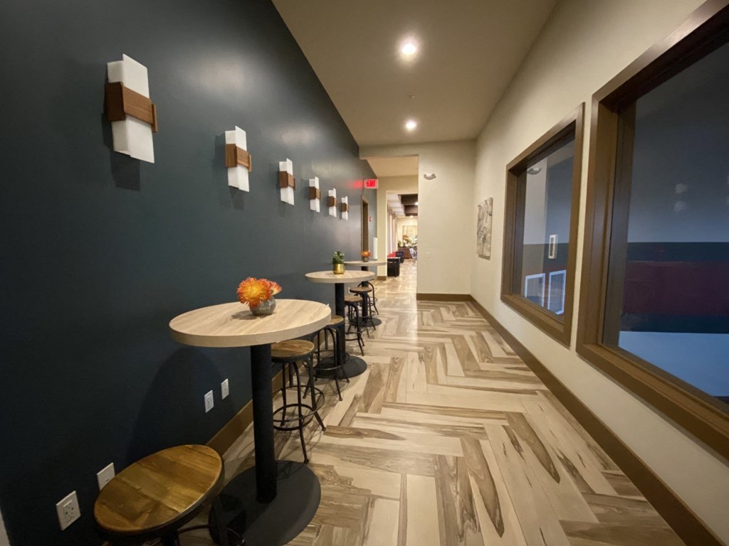 a long corridor with tables and chairs and a large window at The Retreat Apartment Homes in Williston, North Dakota