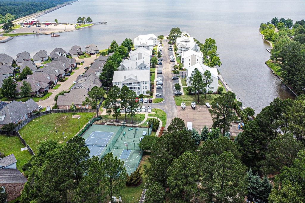 an aerial view of the resort with a tennis court in the foreground and a body of water at Lakeshore Pointe Apartment Homes, Mississippi, 39047