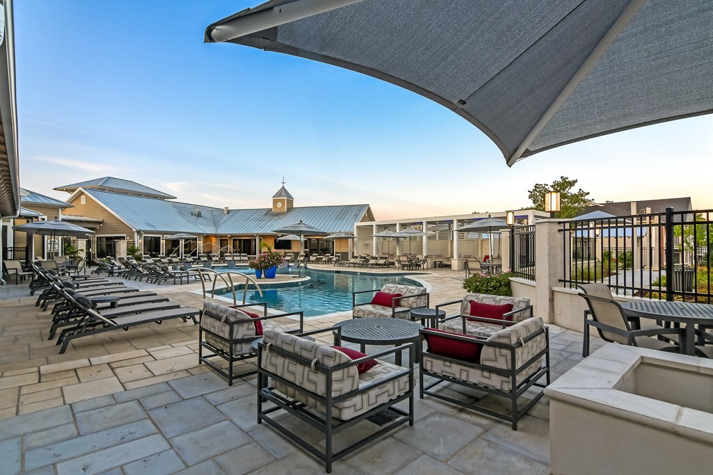 an outdoor patio with tables and chairs and a swimming pool at Crossgates Apartment Homes, Mississippi 39759