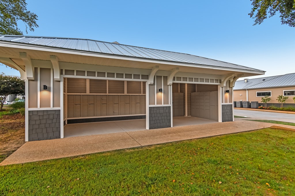 a house with two garage doors and a lawn at Crossgates Apartment Homes, Starkville