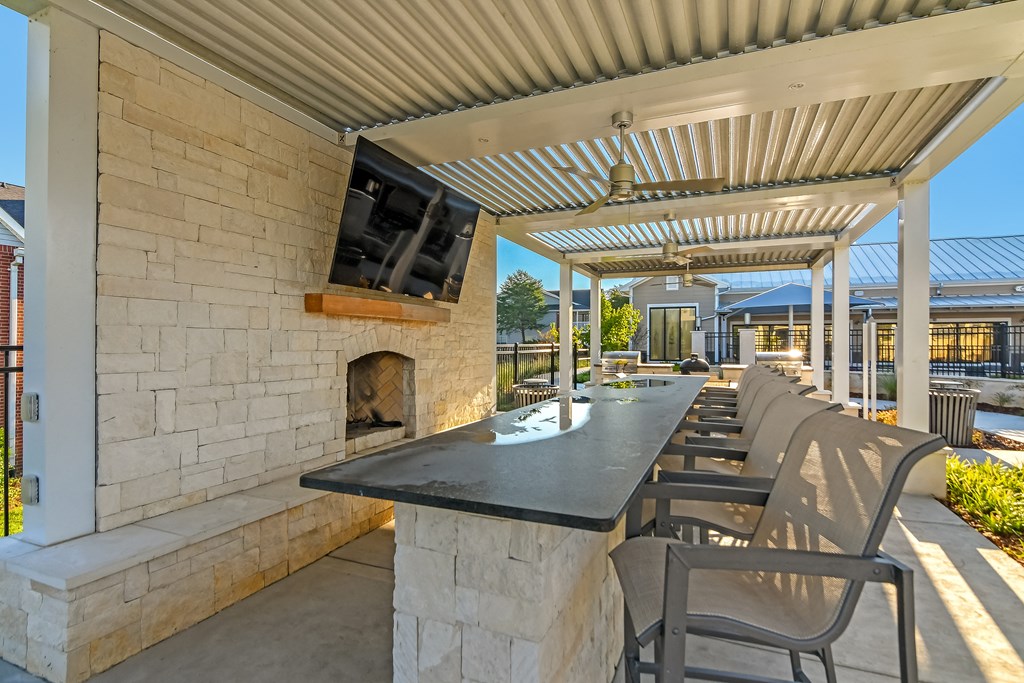 the outdoor patio has a fireplace and a long table with chairs at Crossgates Apartment Homes, Starkville, MS 39759