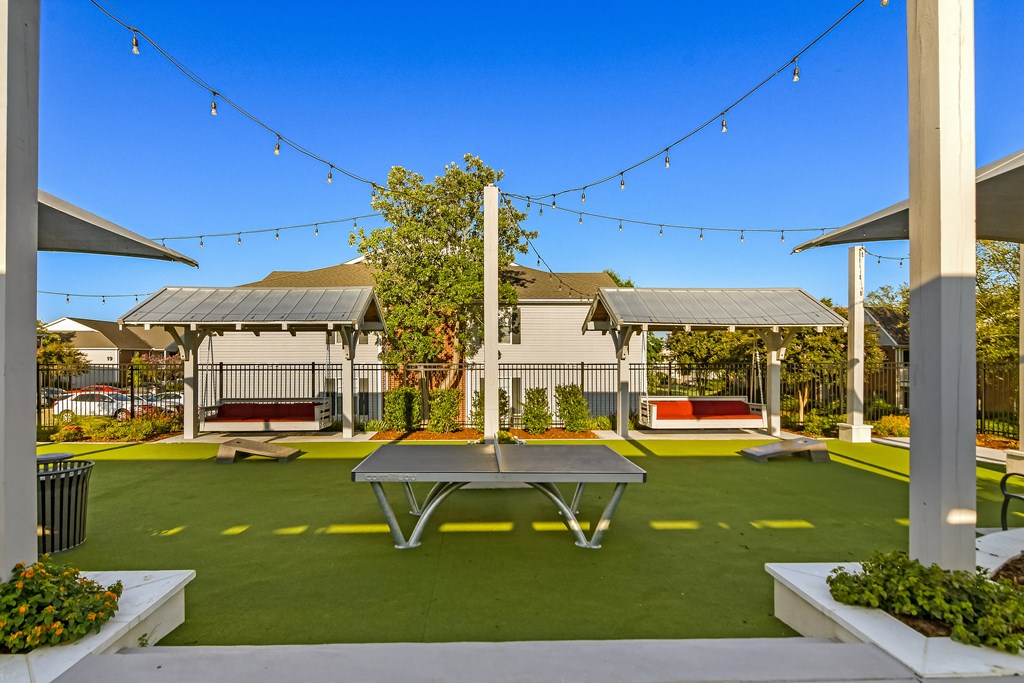 a ping pong table sits in the middle of a courtyard with picnic tables at Crossgates Apartment Homes, Starkville, MS 39759