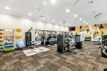 A gym with a variety of equipment including treadmills, weights, and exercise balls at Crossgates Apartment Homes, Mississippi