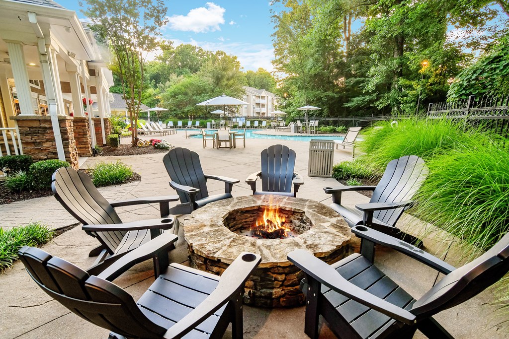 A fire pit surrounded by chairs in a backyard setting.