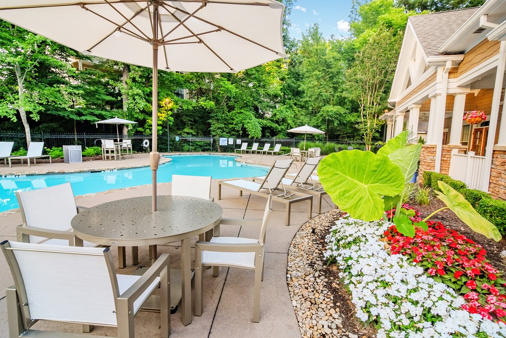 A patio with a table and chairs overlooking a pool.