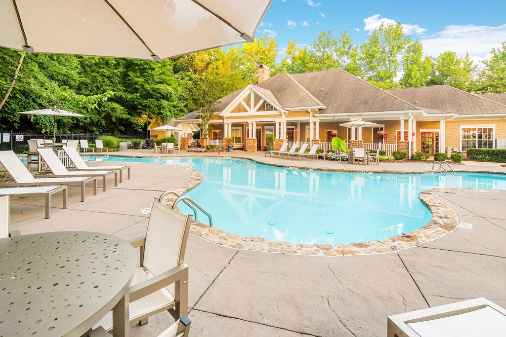 A pool area with a house in the background.