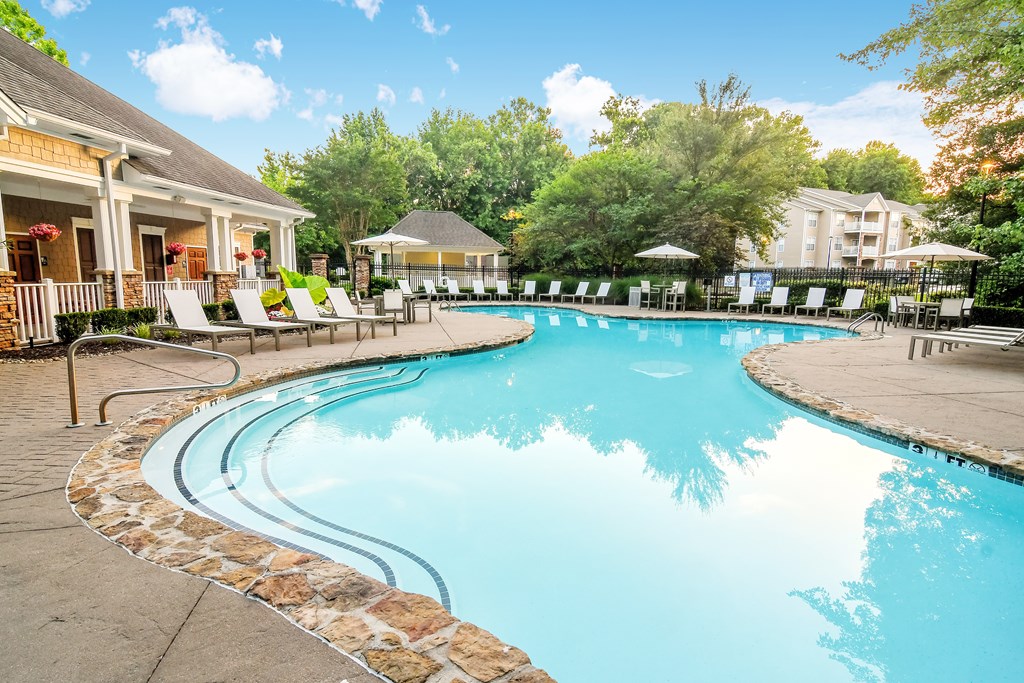 A large swimming pool surrounded by a stone border and lounge chairs.