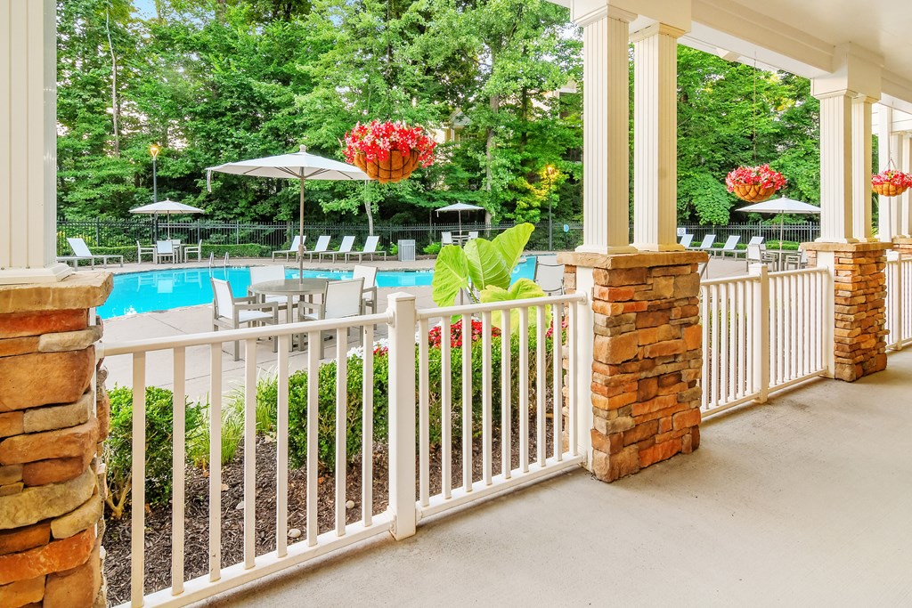 A pool area with a white fence and red flowers.