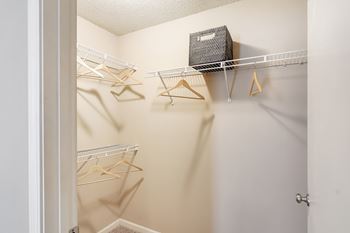 A white closet with a shelf and hangers at Avalon Apartment Homes in Starkville, Mississippi 39759