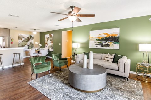 a living room with green walls and a white couch and green chairs