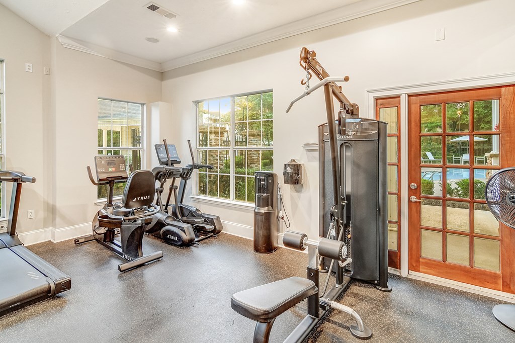 A home gym with a treadmill, elliptical machines, and a weight bench.