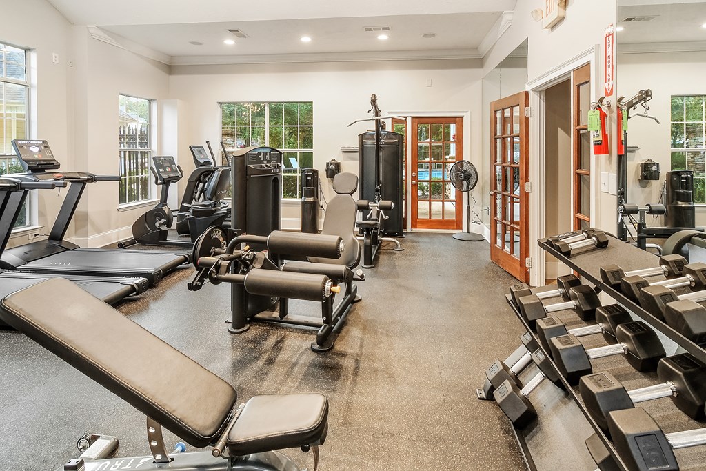 A gym with a variety of equipment including treadmills, weights, and exercise machines.