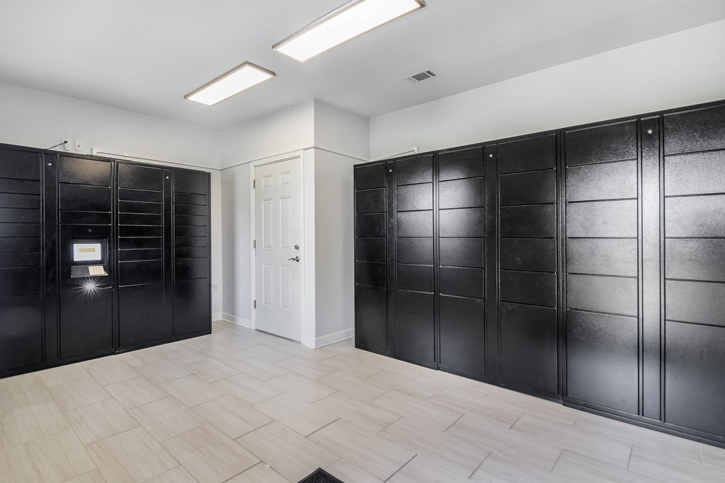 a row of black lockers in a room with a white door at Avalon Apartment Homes in Starkville, MS 39759