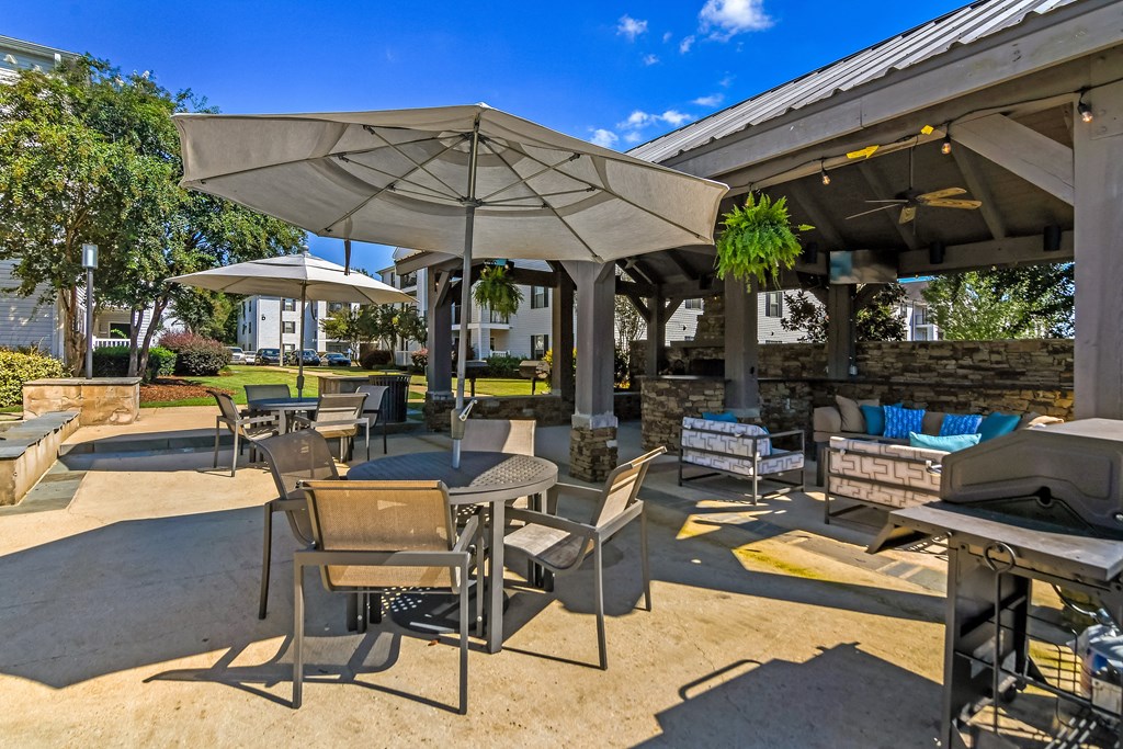 an outdoor patio with tables and chairs and umbrellas at Avalon Apartments Starkville, MS