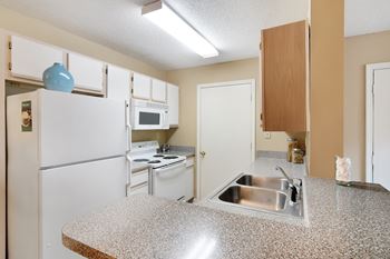 A kitchen with a granite countertop and white appliances at The Colony Apartment Homes in Columbus, MS
