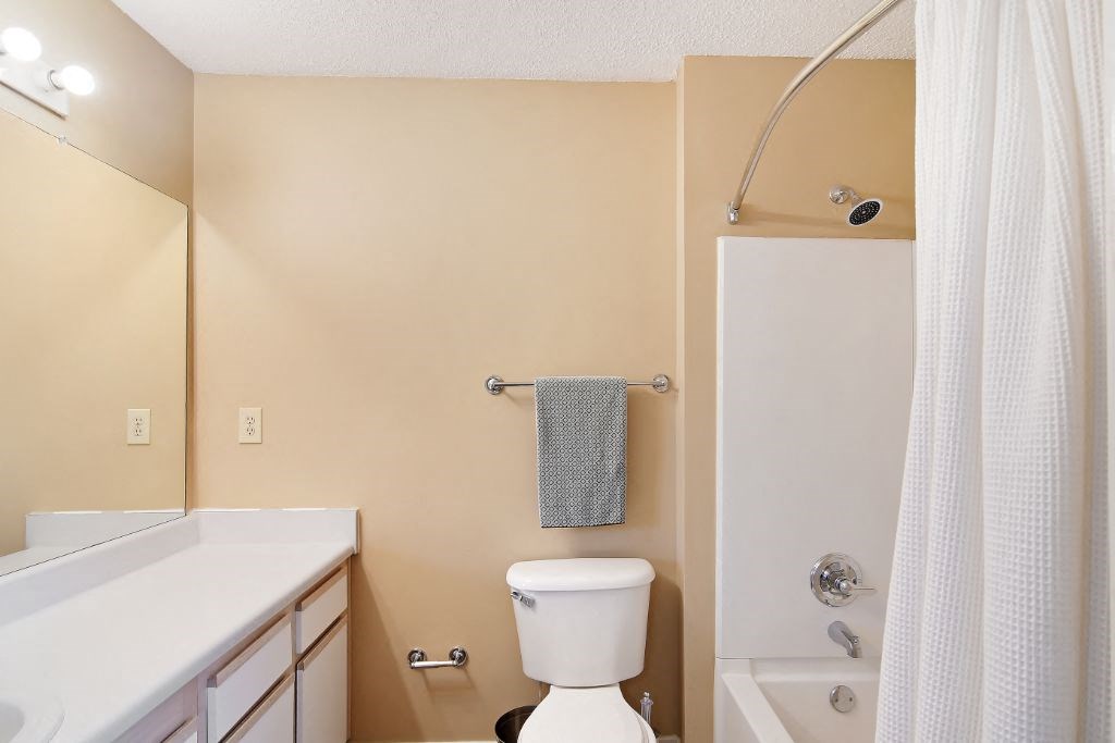 a bathroom with a white sink and toilet next to a white bathtub with a shower curtain at The Colony Apartment Homes, Columbus, 39702