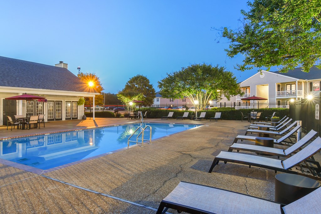 a swimming pool with lounge chairs at night at The Colony Apartment Homes, Columbus, Mississippi
