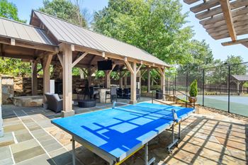 A blue table tennis table is in the middle of a patio Lexington Pointe Apartment Homes in Mississippi 38655