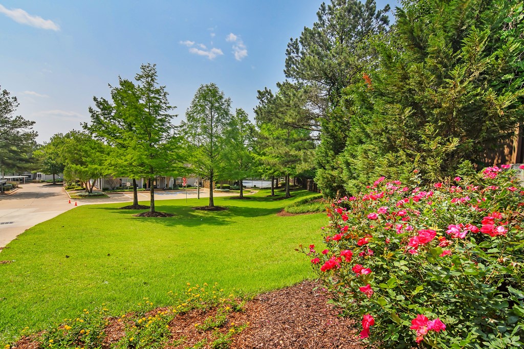 a park with green grass and trees and flowers at Lexington Pointe Apartment Homes in Oxford, MS 