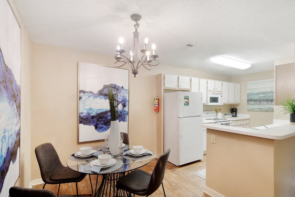 a dining area with a table and chairs and a kitchen in the background at Lexington Pointe Apartment Homes, Oxford, MS